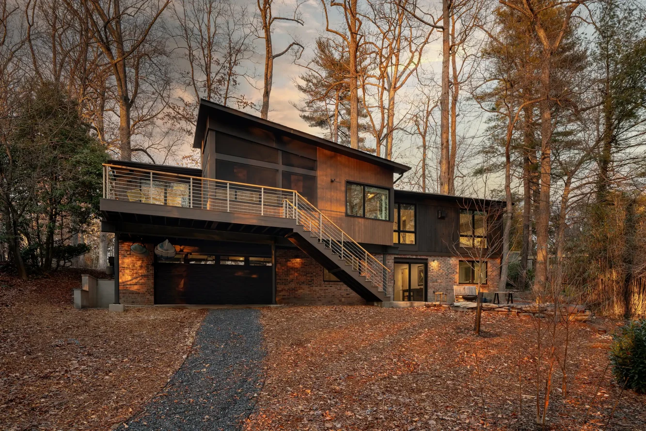 Rear view of the home showing two tone nickel gap cypress siding, new cantilevered library and screened porch and deck / stair addition plus ground level patio