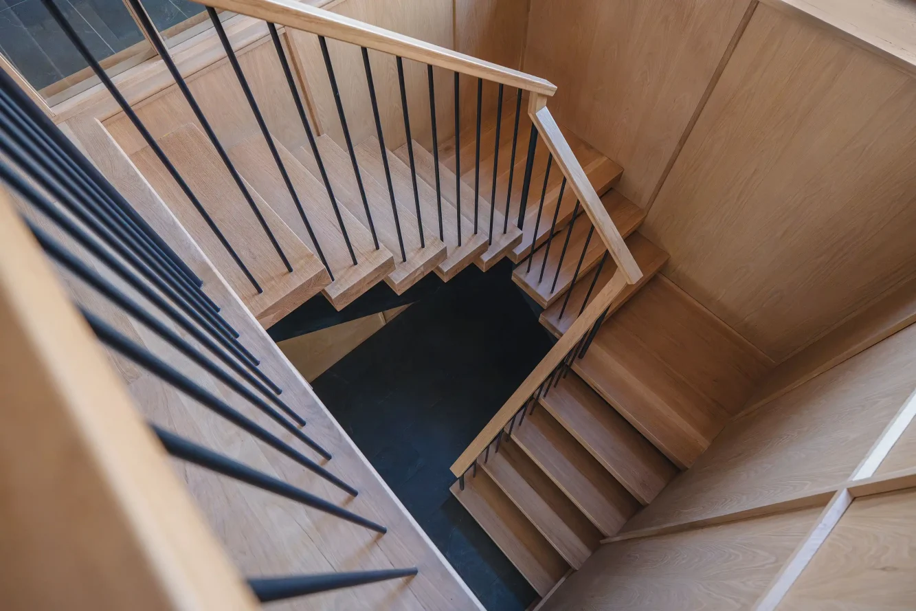 Overhead view of new mcm inspired white oak slab floating stair, white oak handrail and blackened steel picket rail