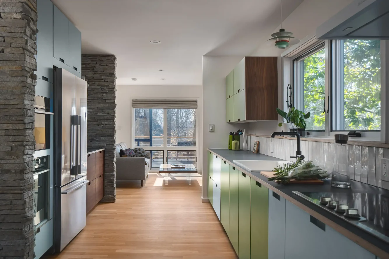 View of mod kitchen toward "snuggery" showing integration of walnut side panels and baltic plywood and laminate cabinet doors and game changing new window over sink