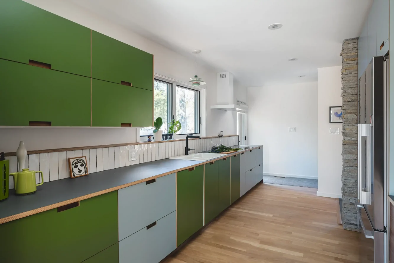 View of new mod kitchen showing playful baltic plywood and laminate cabinet doors, Fenix countertop, white tile backsplash, white oak flooring and minimalistic Futuro exhaust hood